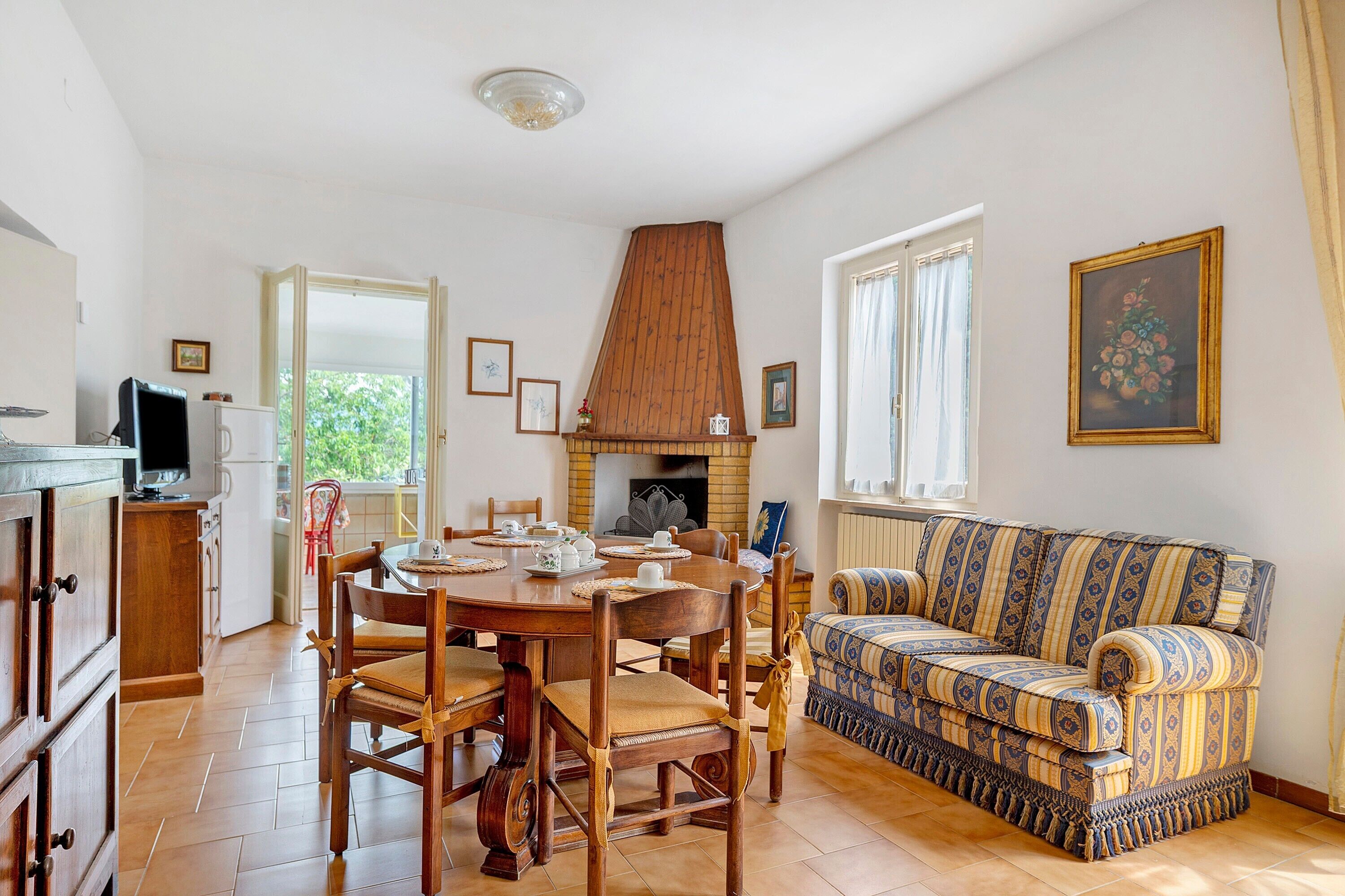 Un coin repas avec une table et des chaises en bois, un canapé et une cheminée.
