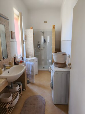 Een moderne badkamer met een douchecabine van glas, een wastafel, een toilet en een wasmachine.