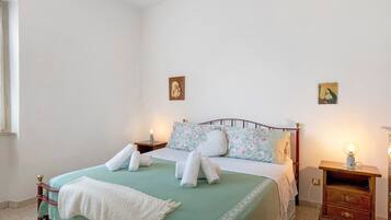 A bedroom with a bed, two bedside tables, a nightstand, and a window.