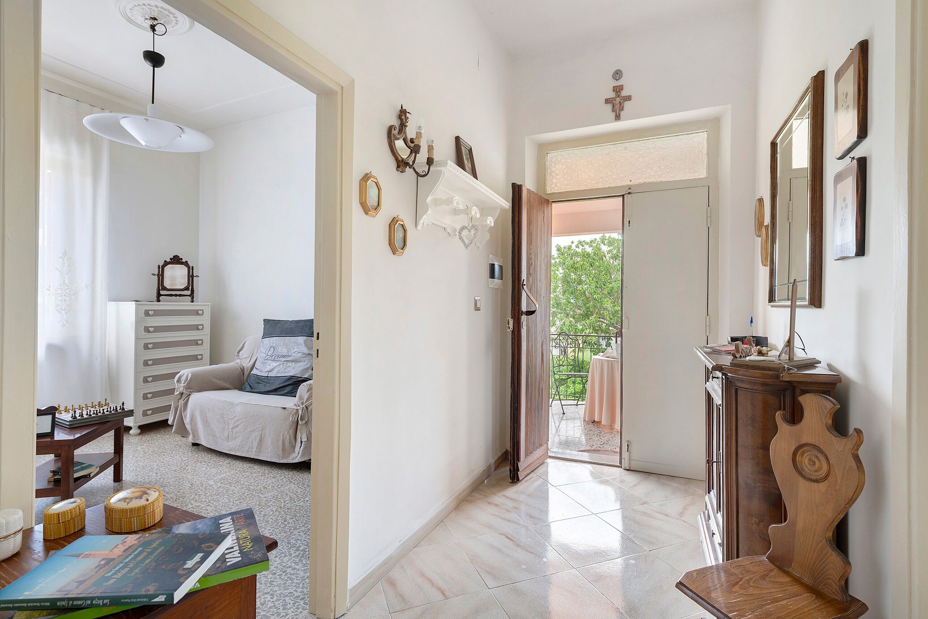 A hallway with a chessboard, a sofa, a wooden cabinet, and a door leading to an outdoor area.