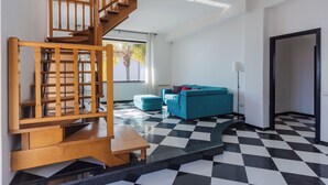 Un interior modern amb una escala de fusta, un sofà blau i un paviment a escacs.