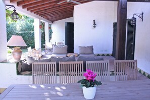 Une terrasse extérieure avec une table en bois, des chaises, un canapé et une plante en pot.