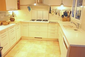 A kitchen with white cabinets, a stove, a sink, and a window with a view.