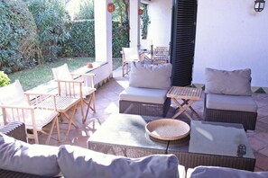 Une terrasse extérieure aménagée avec des meubles en osier, notamment des canapés et des fauteuils, ainsi qu’une table à manger.