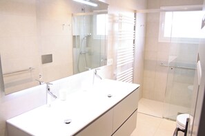 A bathroom with a large mirror, a white sink, a shower enclosure, and a toilet. - Splendid marina villa (Cambrils)