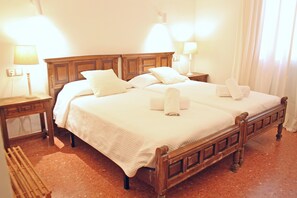Ein Doppelbett mit Holz-Kopfseitenverkleidung, zwei Nachttische mit Lampen und eine Sitzbank.
