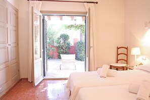 Une chambre d’hôtel avec un lit, une chaise, une table et une vue sur un patio extérieur.