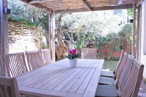 Une table en bois avec des chaises, une plante en pot et une structure de pergola.