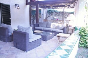 Une terrasse extérieure avec des meubles en osier, une table et une lampe.