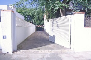 A narrow alleyway with a white gate, stone pavement, and a tree-lined path. - Splendid marina villa (Cambrils)
