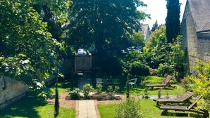A garden with a paved path, a small tree, and a bench. - La Fleur de Lys (Langeais)
