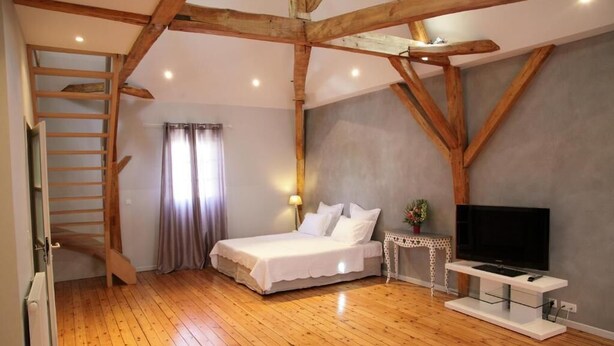 A bedroom with a wooden ceiling, a bed, a TV, and a small table. - La Fleur de Lys (Langeais)