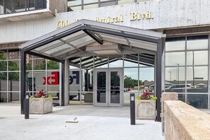 Entrada de un edificio con un vestíbulo cubierto, puertas de vidrio y un letrero que dice '600 Antrim Blvd'.