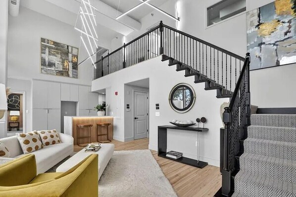 Amplia sala de estar con una escalera, un sofá, una mesa de centro y una chimenea.