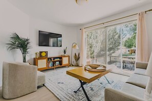 Ein modernes Wohnzimmer mit einer Couch, einem Couchtisch, einem Fernseher und einem Bücherregal.