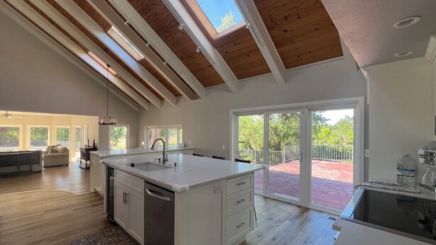 A spacious kitchen with a large island, wooden beams, and a sliding glass door to a patio. - Waterfront POOL with 4100 sqft home in the Country. Fish too! (Millville)