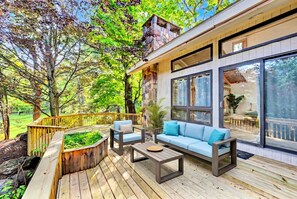 A deck with outdoor furniture, a stone fireplace, and large windows overlooking a garden. - #1 Celebrity Mansion Estate Huge Dance Floor &  Pool Pickleball Secret Speakeasy (East Stroudsburg)