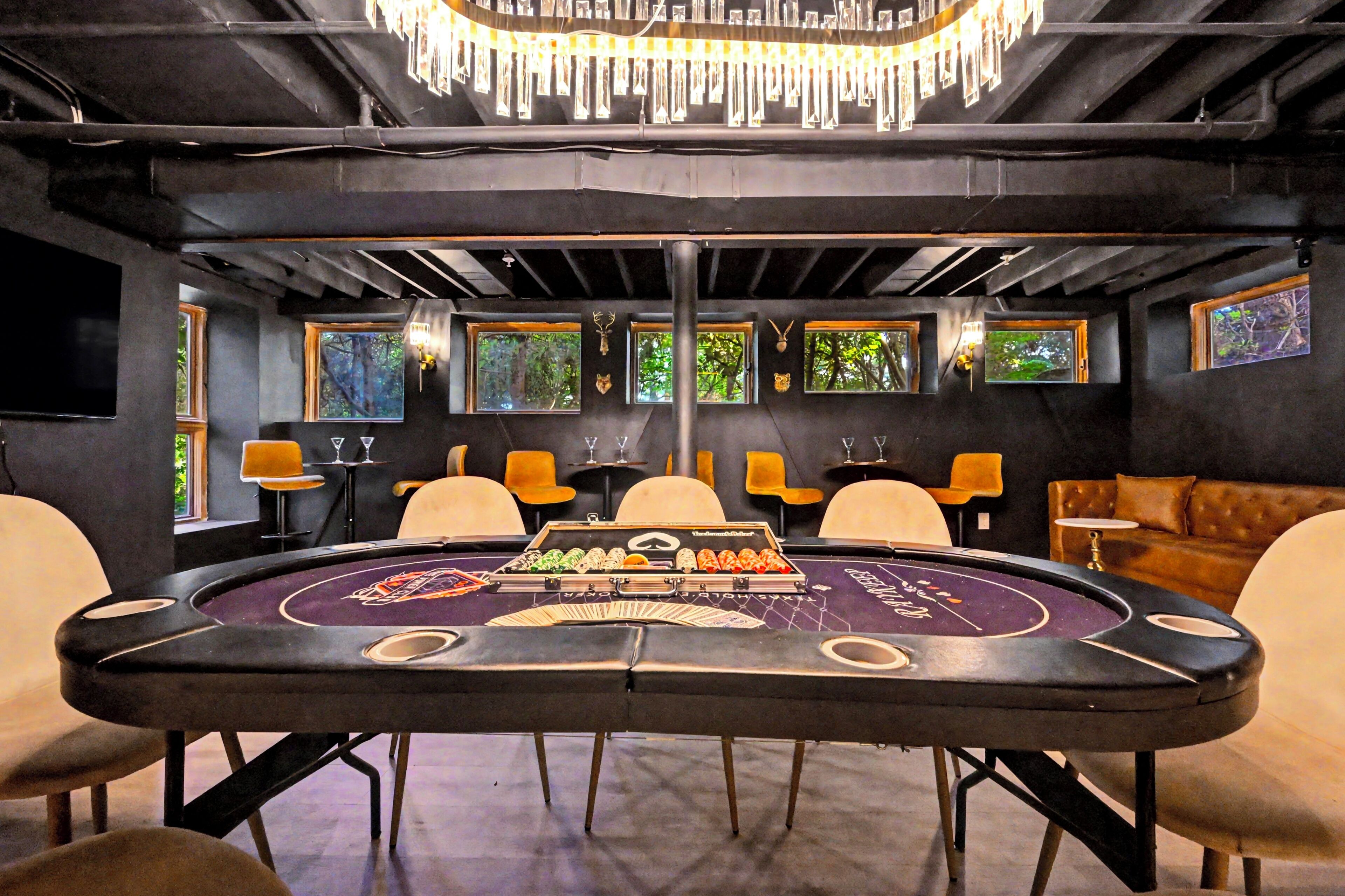 Una mesa de casino con sillas, una araña y cuadros en las paredes.