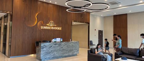 A modern reception area with a wooden wall, a marble reception desk, and a seating area with a sofa and a coffee table.