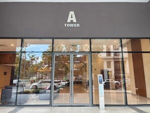 Ein Hotel mit Eingangsbereich, einer großen Glasfassade, einem Schild mit der Aufschrift 'A TOWER' und einem Parkplatz, der durch die Fenster sichtbar ist.
