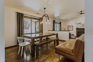 Ein Essbereich mit Holztisch und Stühlen, einer Couch, einem Kamin und einem Deckenventilator.