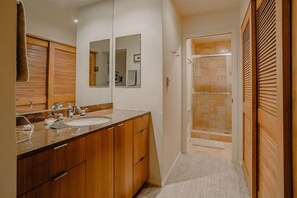 Un baño con armarios de madera, un lavabo, un espejo y una ducha.