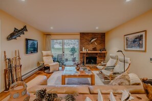 Una sala de estar con chimenea, un sofá, una mesa de centro y una televisión.