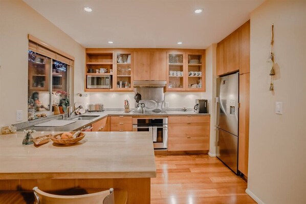 Una cocina moderna con armarios de madera, electrodomésticos de acero inoxidable y una isla central.