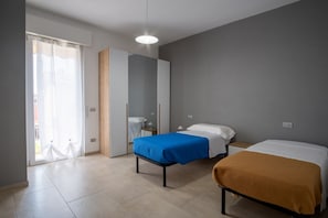 A modern bedroom with two beds, a wardrobe, a mirror, and a sliding door to a balcony. - A cozy 100 square meters apartment, perfect for six people, located on the first floor of a building without an elevator.The property is located in Quarto, a small village in the municipality of Gossolengo. The location is ideal for those seeking a relax (Quarto)