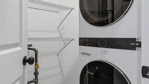 A laundry room with two stacked washing machines, a metal drying rack, and a door with a towel dispenser. - 3-bedroom apartment in lovely Chicago with AC and comfort (Chicago)