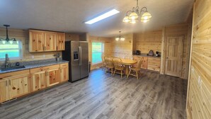 Una cucina con mobili in legno, un frigorifero, un tavolo da pranzo con sedie e un lampadario.