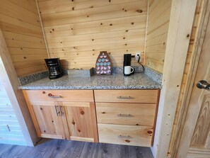 A wooden cabin interior with a kitchen counter, coffee maker, mug, and a decorative item.