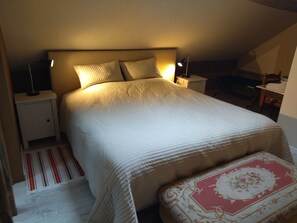 Una camera da letto con un letto, abat-jour, comodino, una panca e un tappeto decorato.