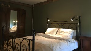 Ein Bett mit Metallgestell, eine Nachttischlampe und ein Spiegel an der Wand.