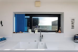 A modern bathroom with a large window, a white sink, and a mirror.