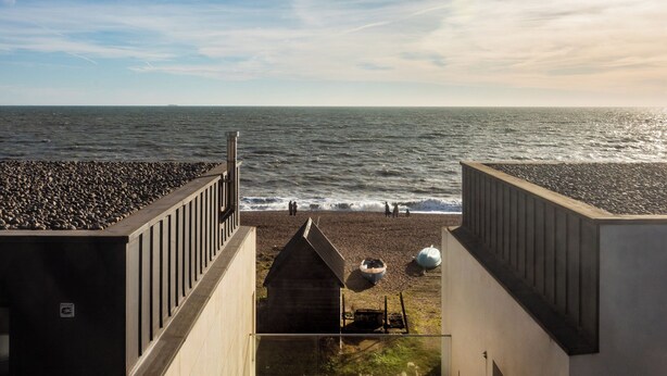 A beach view from a building with a sloped roof, a small wooden structure, and a pebble beach. - Stylish Townhouse with Panoramic Sea Views | Near Beach, Canal & High Street (Hythe)