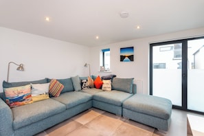 A modern living room with a sectional sofa, a floor lamp, and a painting on the wall.