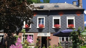 A two-story building with a dark facade, white window frames, and flower boxes on the upper floor.