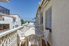 Un balcone con tavolo e sedie, vista su una distesa d'acqua ed edifici.