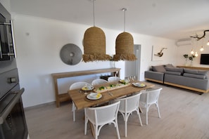 A dining area with a wooden table, white chairs, and hanging woven light fixtures. - Harmony Villa 2 (Karpathos)