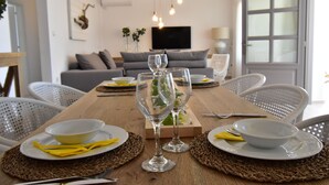 Mesa de jantar posta com pratos, tigelas e copos de vinho, cercada por cadeiras.