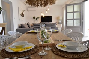Een eettafel gedekt met borden, kommen en wijnglazen, omringd door stoelen.