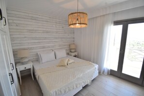 Een slaapkamer met een bed, nachtkastjes, een lamp, een raam met gordijnen en uitzicht op de omgeving.