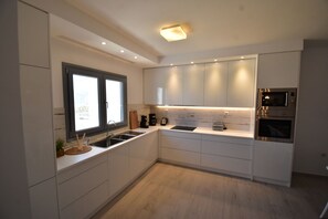 Een moderne keuken met witte kastjes, een ingebouwde magnetron en een raam.