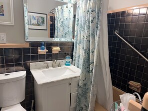 Un baño con lavamanos, espejo, inodoro y cortina de ducha.