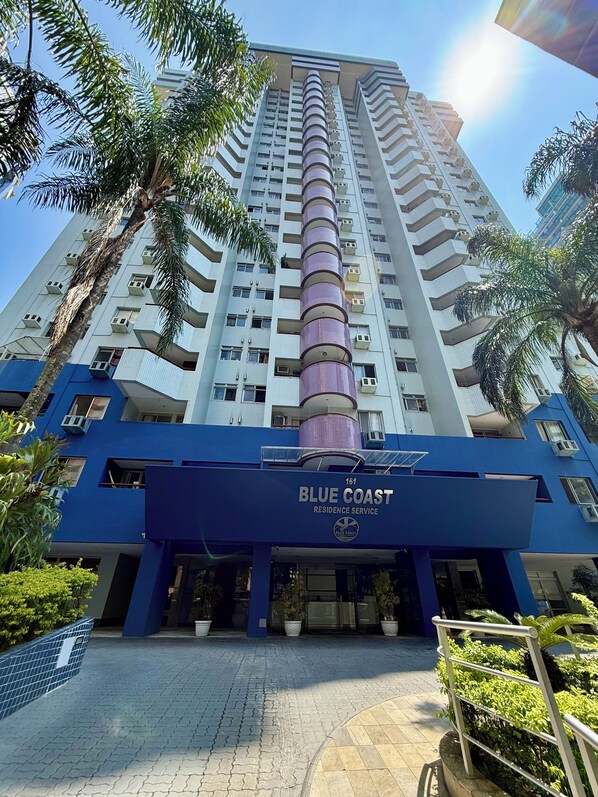 Ein Hochhaus mit blauer Fassade und einem markanten vertikalen Element, mit der Aufschrift 'Blue Coast Residence Service'.
