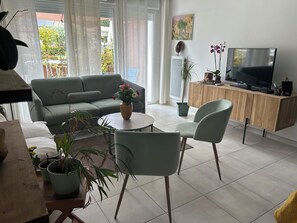 A living room with a sofa, a coffee table, chairs, a TV, and potted plants. - Natura residence near salagou (Clermont-l'Hérault)