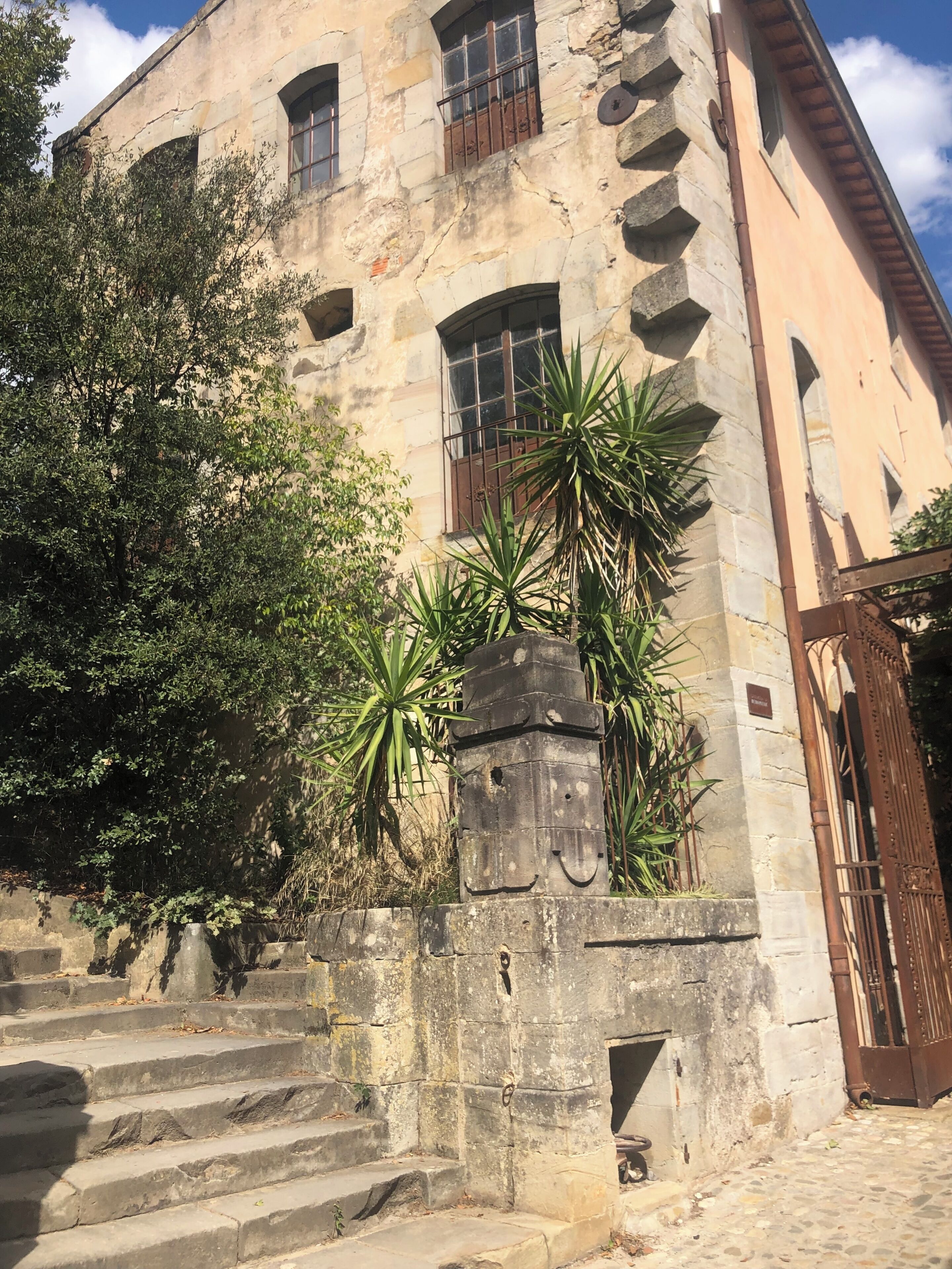 Un edificio de piedra con ventanas arqueadas, una escalera y una reja de metal.