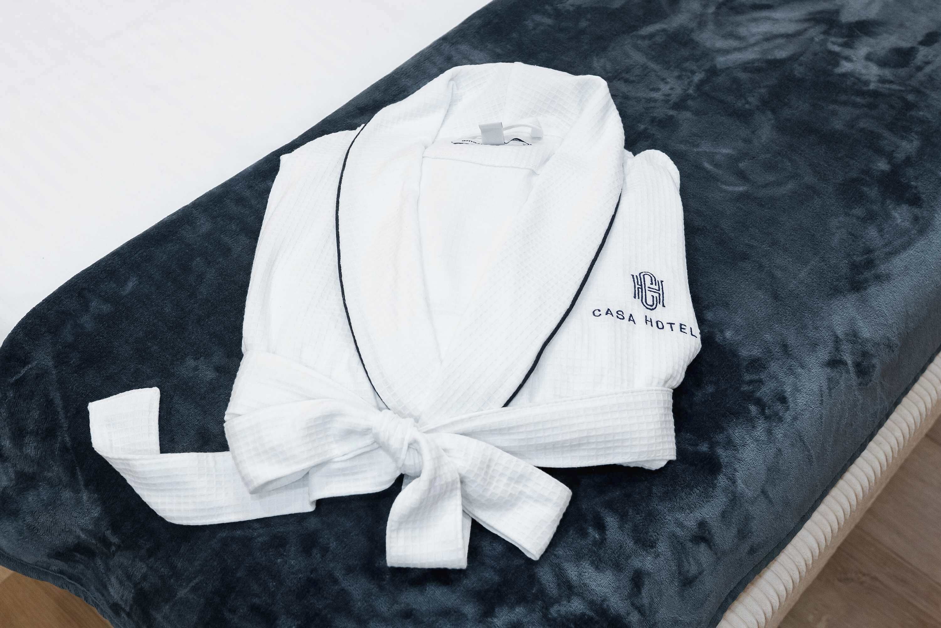 A white robe with a bow tied at the front, placed on a dark blue cushioned surface.