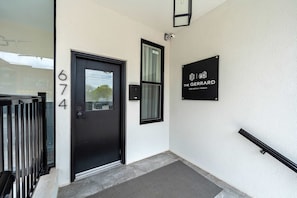 Eine schwarze Tür mit der Nummer 674, ein schwarzes Schild mit dem Logo 'The Gerrard' und ein schwarzes Geländer auf der rechten Seite.